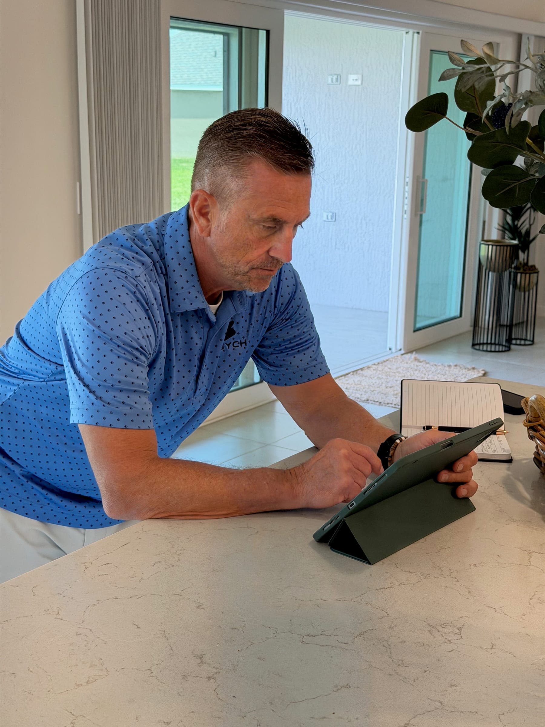 Kevin Kirk Burzynski reviewing listings on a tablet at a kitchen counter